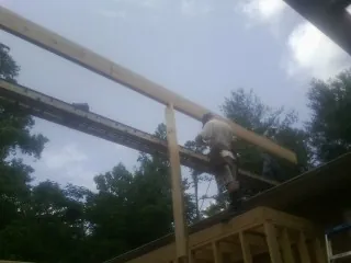 Carpenter setting a ridge beam over a new addition frame — Ice Dam Removal by Roofing Brothers in Canton Center