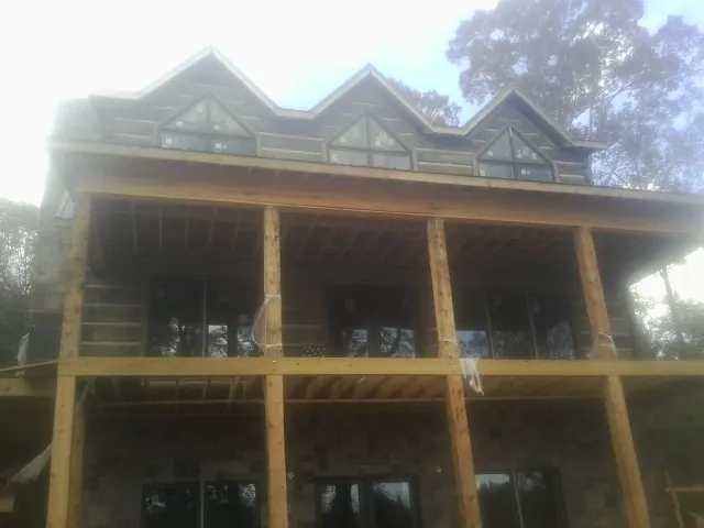 Dormers and porch framing on a large log home under construction — Roof Coating work by our crew in Canton Center