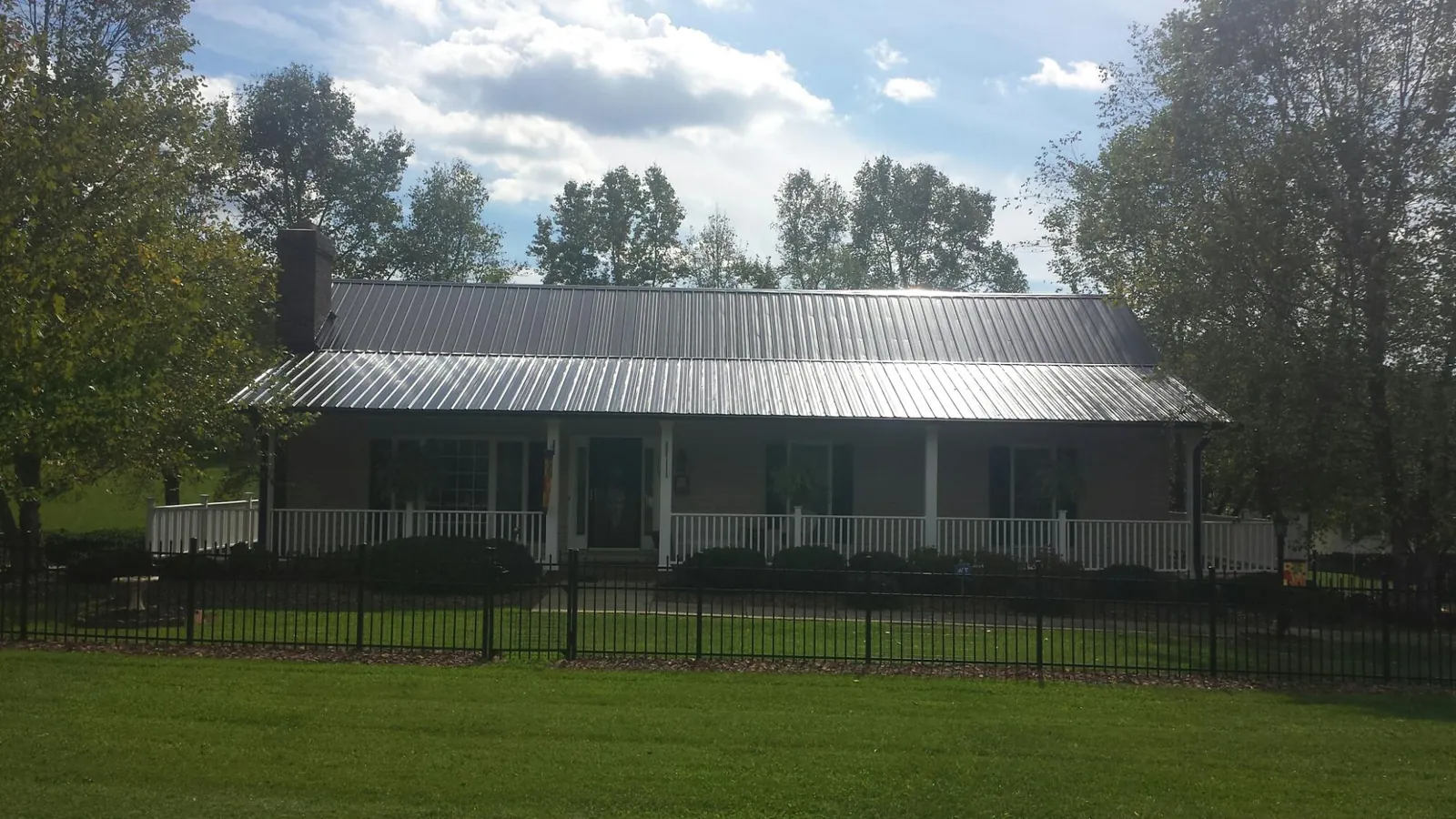 Gray metal roof on a brick ranch with a full width front porch — Gutter Guard Installation work by our crew in Canton Center