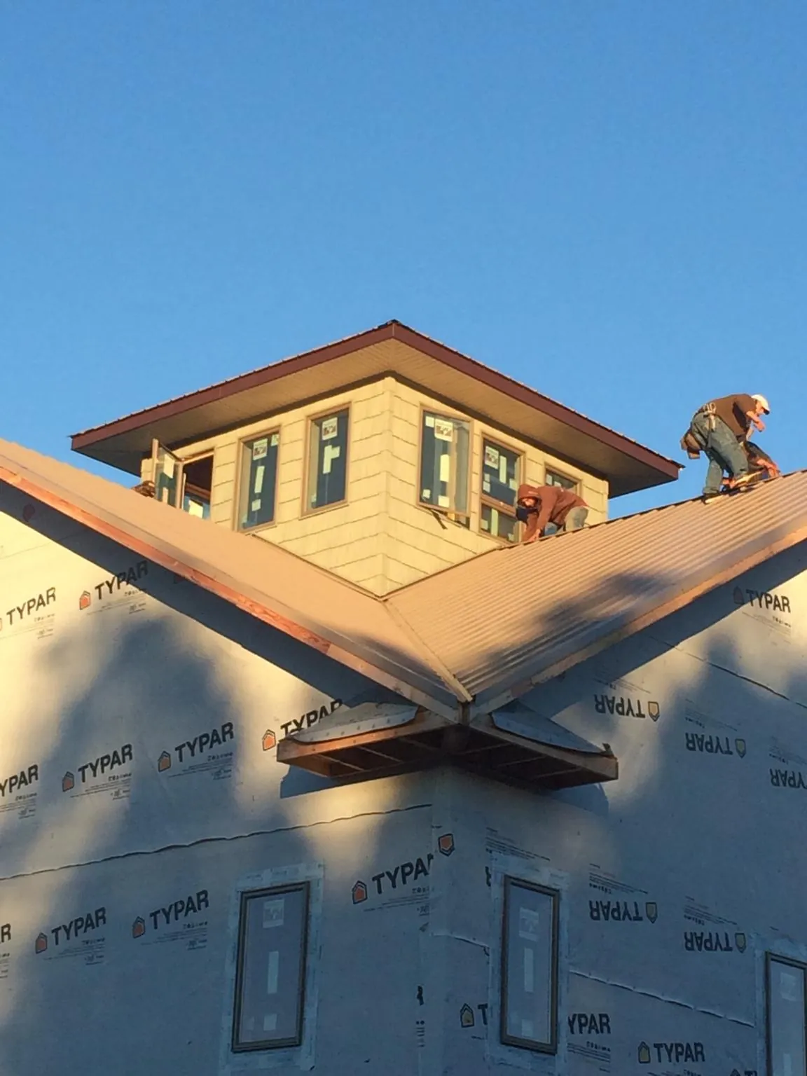 Roofers working around a rooftop cupola on a new metal roof at sunset — Roof Waterproofing in Canton Center by Roofing Brothers